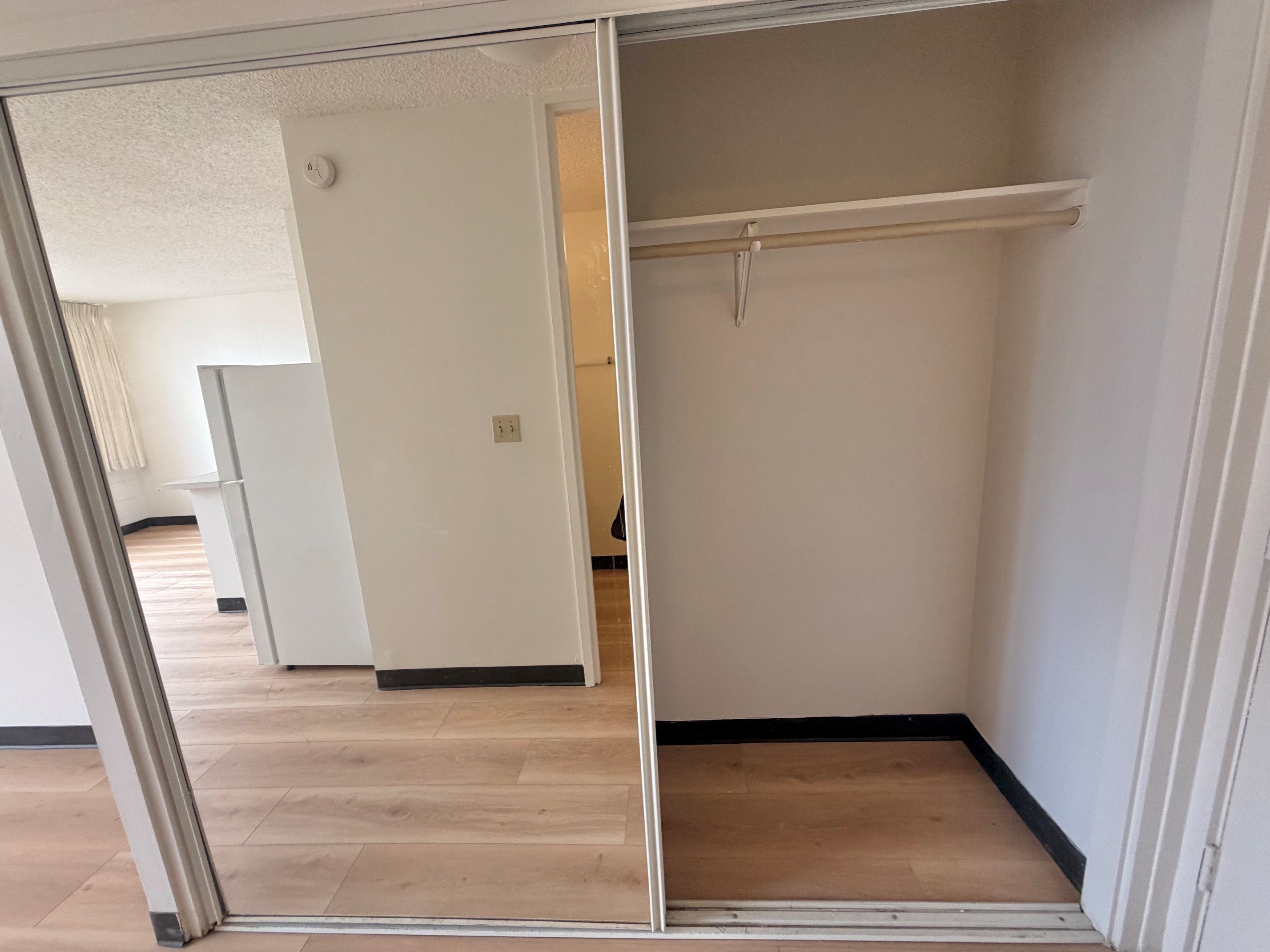 A white closet with a mirror on the door.